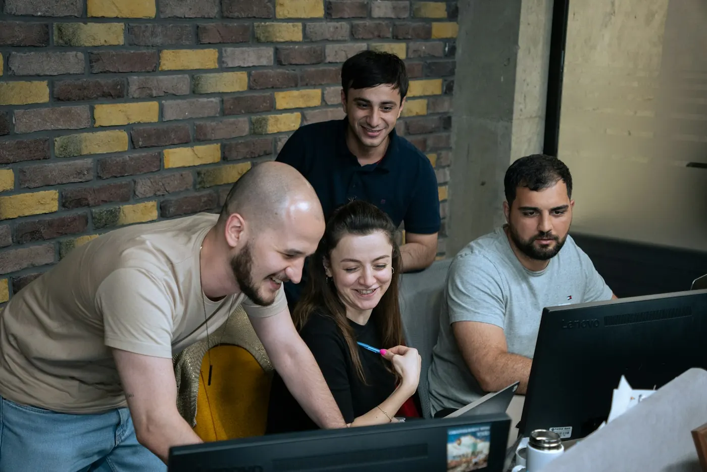 Four colleagues gathered around a monitor reviewing work together
